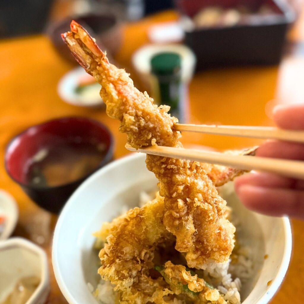 天丼の海老を箸で持ち上げる写真